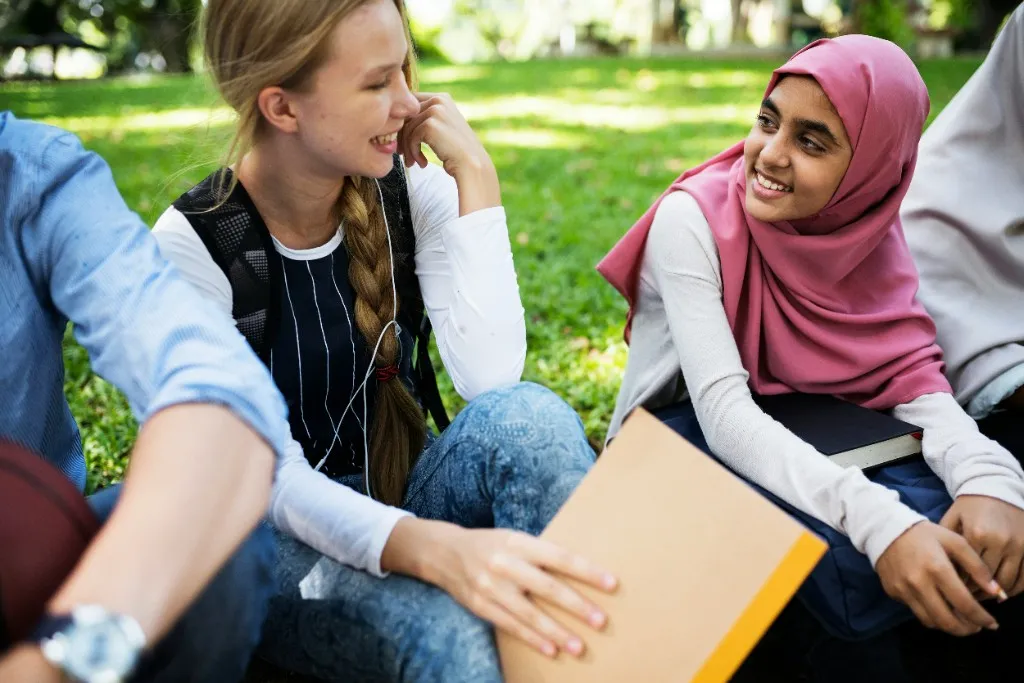 Diverse students talking together on a campus lawn